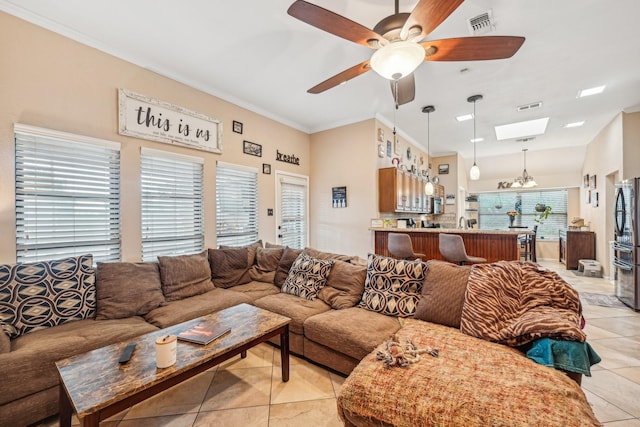 tiled living room featuring ornamental molding, a healthy amount of sunlight, ceiling fan with notable chandelier, and a skylight