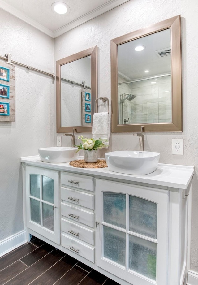 bathroom featuring walk in shower, ornamental molding, and vanity