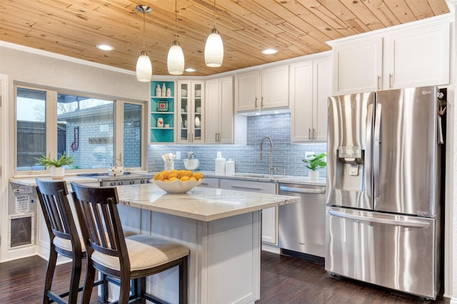 kitchen featuring sink, a center island, appliances with stainless steel finishes, light stone countertops, and white cabinets