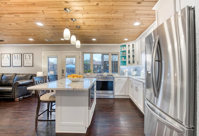 kitchen featuring french doors, light stone counters, hanging light fixtures, stainless steel appliances, and white cabinets