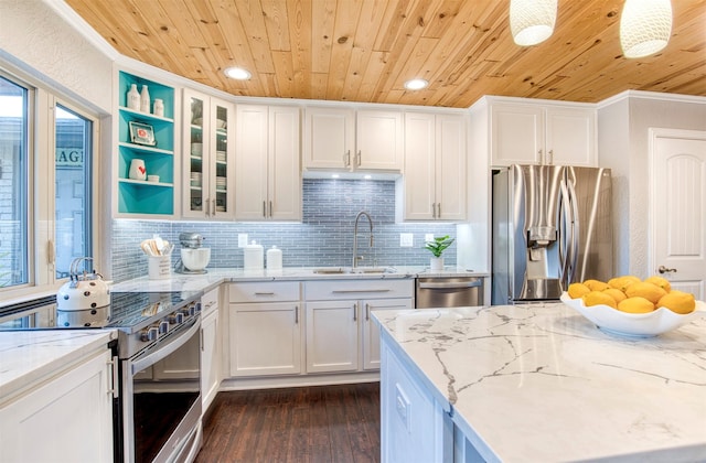 kitchen with sink, appliances with stainless steel finishes, hanging light fixtures, light stone counters, and white cabinets