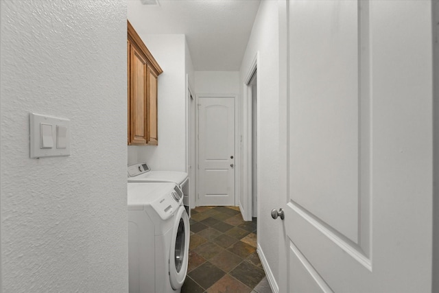 clothes washing area featuring cabinets and washing machine and dryer