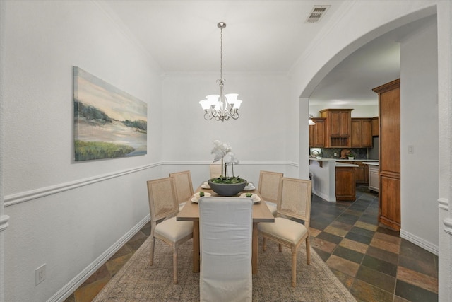 dining room with ornamental molding and an inviting chandelier