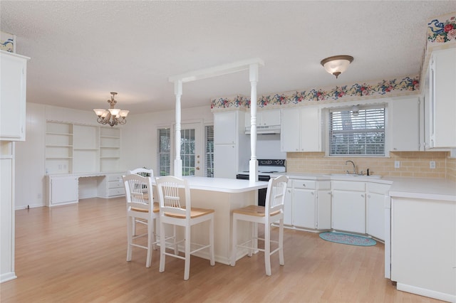 kitchen featuring electric stove, a center island, hanging light fixtures, and white cabinets