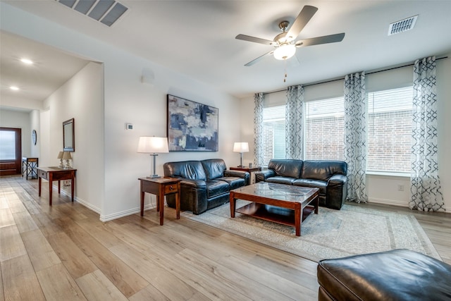 living room with light wood finished floors, visible vents, and baseboards