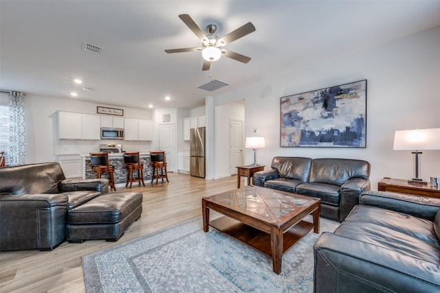 living room with ceiling fan, light wood finished floors, visible vents, and recessed lighting