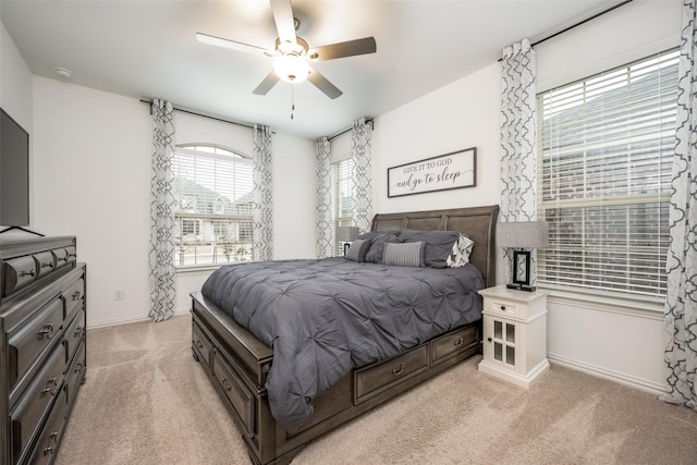 bedroom featuring light carpet, a ceiling fan, and baseboards