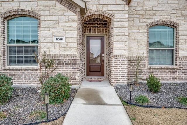 view of exterior entry with stone siding and brick siding