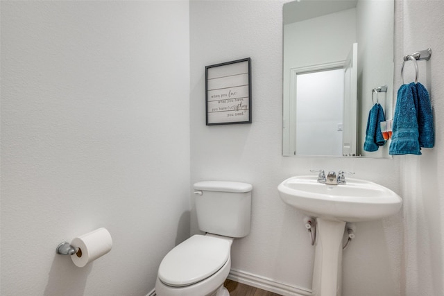 bathroom featuring baseboards, a sink, toilet, and wood finished floors