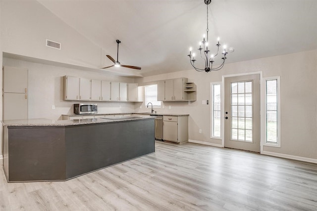 kitchen featuring light stone counters, vaulted ceiling, light hardwood / wood-style flooring, kitchen peninsula, and stainless steel appliances