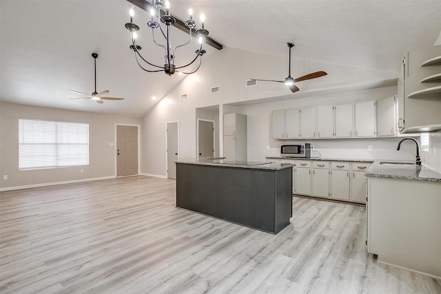 kitchen with white cabinetry, sink, ceiling fan with notable chandelier, and a kitchen island