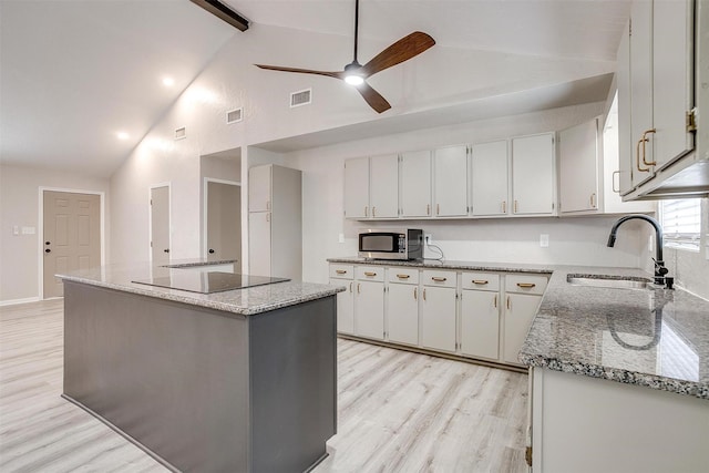 kitchen featuring white cabinetry, sink, light stone countertops, and a kitchen island