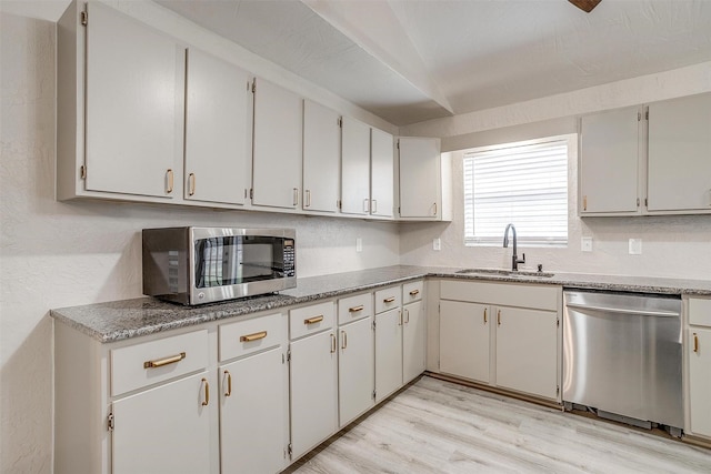 kitchen with sink, white cabinets, stainless steel appliances, light hardwood / wood-style floors, and backsplash