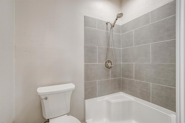 bathroom featuring tiled shower and toilet