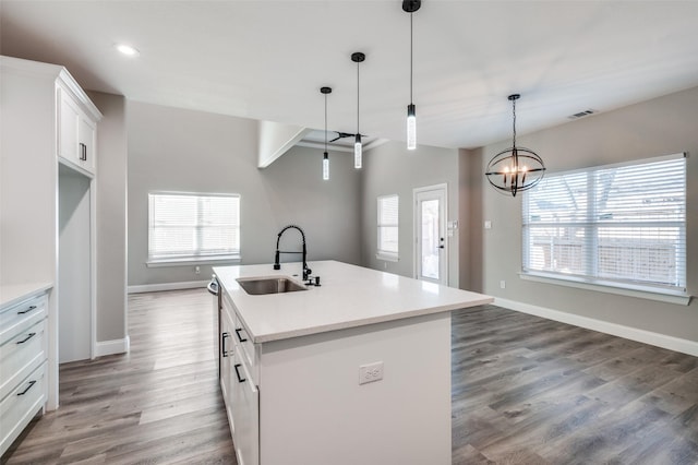 kitchen with pendant lighting, sink, white cabinetry, a healthy amount of sunlight, and a center island with sink