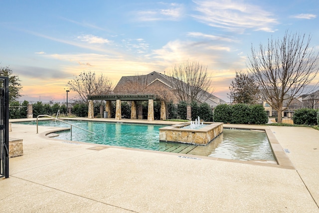 pool at dusk featuring pool water feature and a pergola