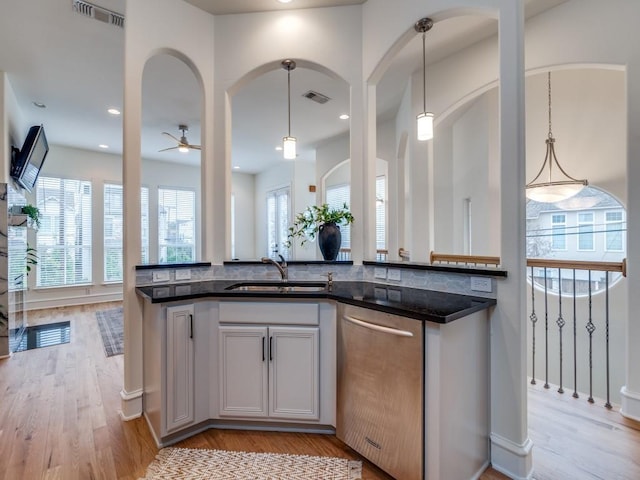 kitchen with decorative light fixtures, white cabinetry, sink, dark stone countertops, and stainless steel dishwasher