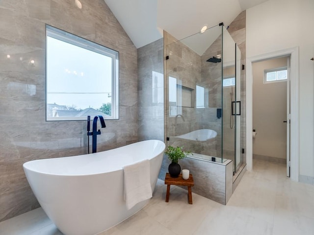 bathroom featuring lofted ceiling, shower with separate bathtub, tile walls, and plenty of natural light