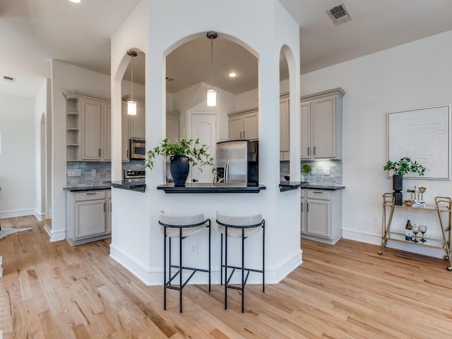 kitchen featuring gray cabinets, appliances with stainless steel finishes, and decorative light fixtures