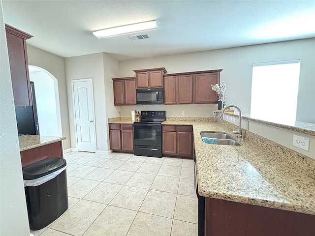 kitchen featuring sink, light tile patterned floors, light stone counters, black appliances, and a textured ceiling