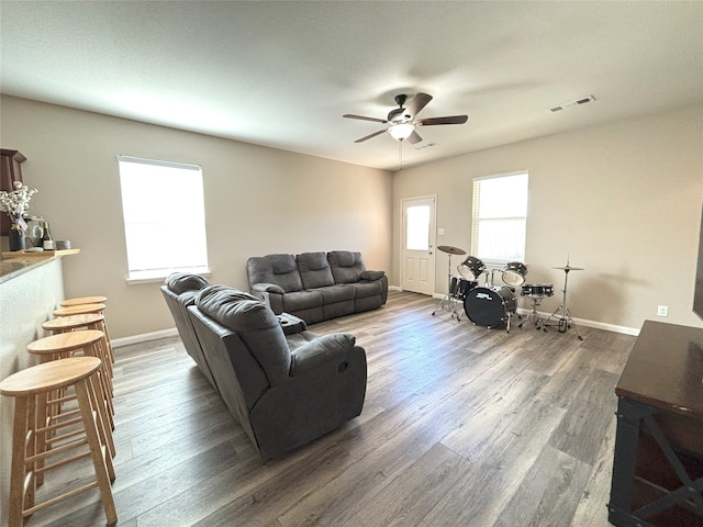 living room featuring dark wood-type flooring, ceiling fan, and plenty of natural light