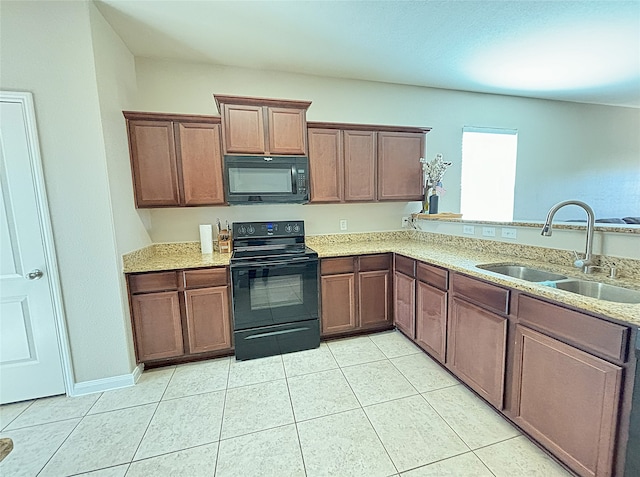 kitchen with light stone counters, sink, light tile patterned floors, and black appliances