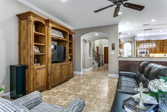 living room featuring baseboards, visible vents, arched walkways, and crown molding