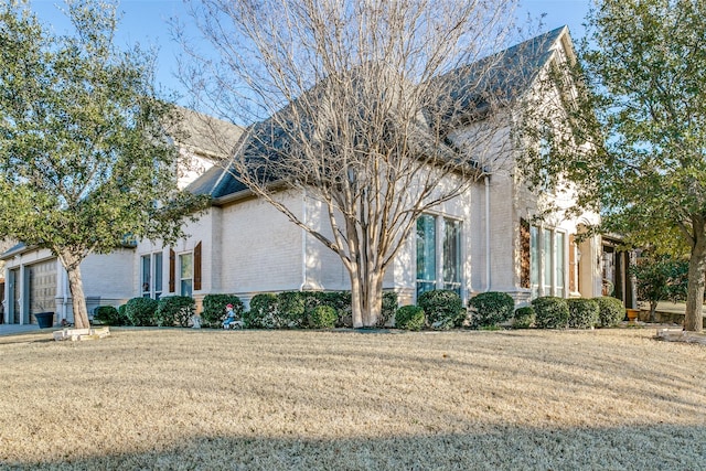 view of property exterior with a garage, brick siding, and a lawn