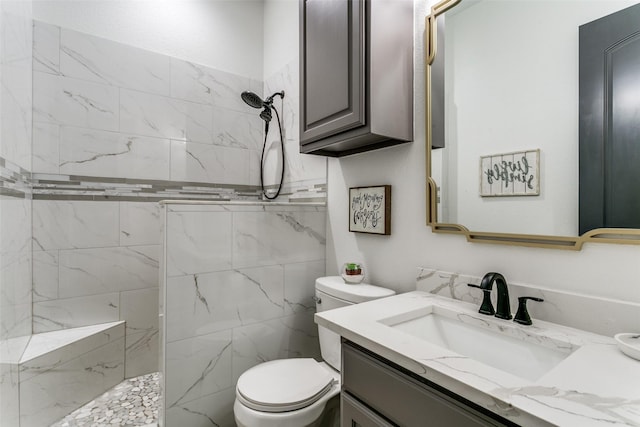 bathroom with toilet, a marble finish shower, and vanity