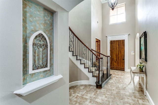 foyer with baseboards, a high ceiling, and stairway