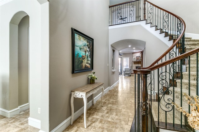 foyer with a towering ceiling, stairway, baseboards, and arched walkways