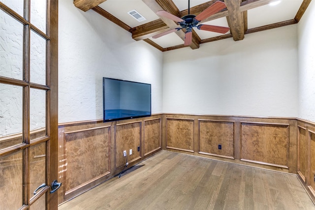 interior space with a wainscoted wall, coffered ceiling, visible vents, light wood-type flooring, and beamed ceiling