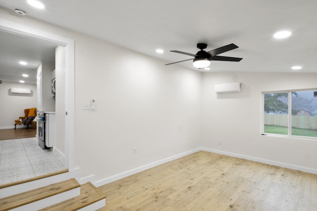 empty room featuring lofted ceiling, a wall unit AC, ceiling fan, and light wood-type flooring