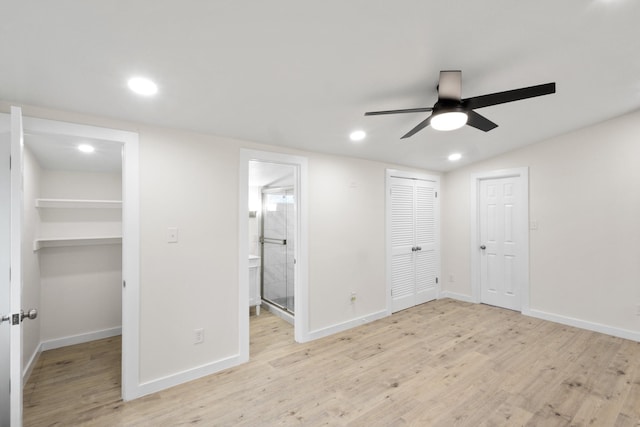 unfurnished bedroom featuring connected bathroom, a spacious closet, ceiling fan, light wood-type flooring, and a closet