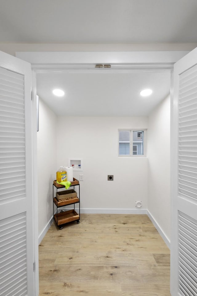 clothes washing area featuring washer hookup, light hardwood / wood-style flooring, and electric dryer hookup