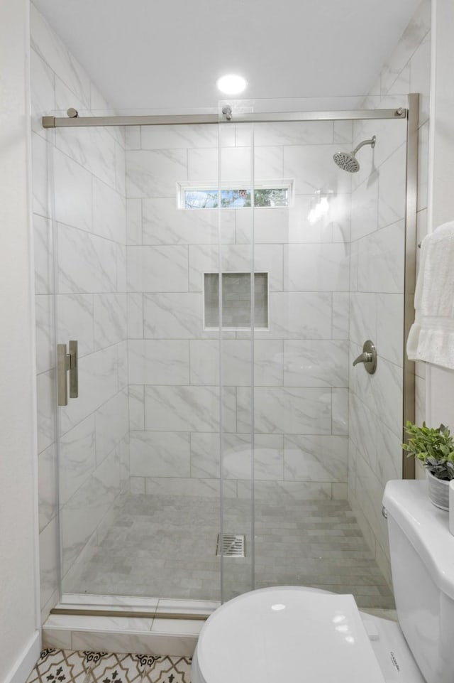 bathroom featuring a shower with door and toilet