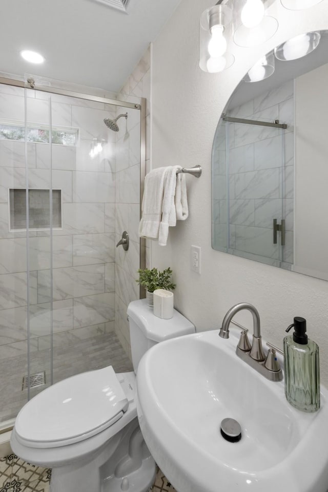 bathroom featuring an enclosed shower, sink, and toilet