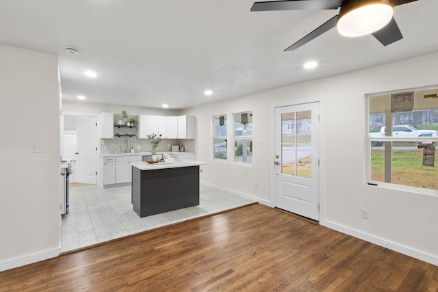 kitchen with white cabinetry, backsplash, a center island, ceiling fan, and light hardwood / wood-style floors