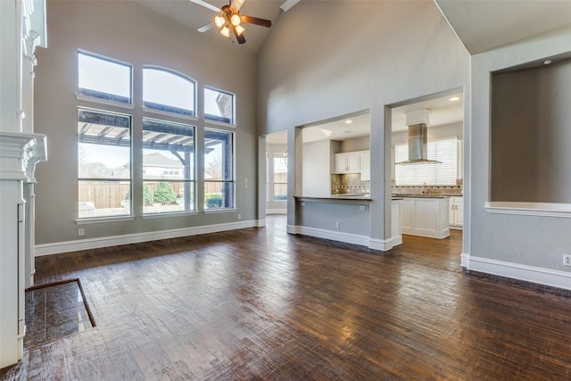 unfurnished living room with ceiling fan, high vaulted ceiling, sink, and dark hardwood / wood-style flooring