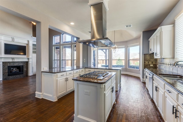 kitchen featuring appliances with stainless steel finishes, tasteful backsplash, island range hood, white cabinets, and kitchen peninsula