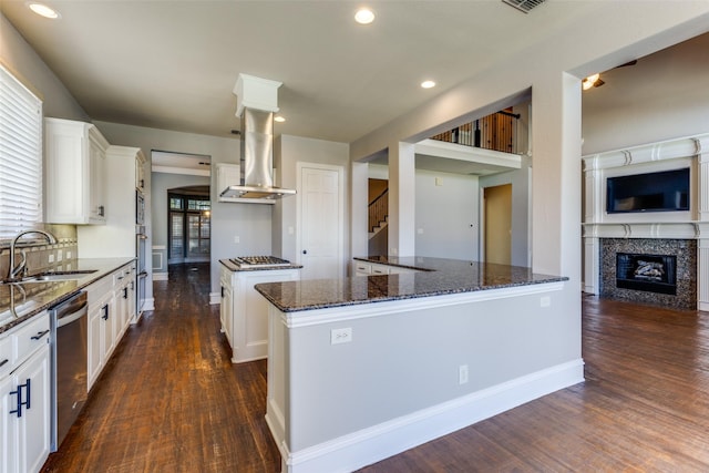 kitchen featuring sink, white cabinetry, stainless steel appliances, a center island, and dark stone counters