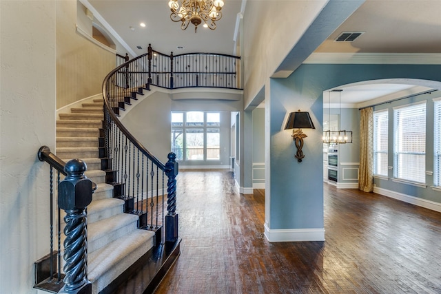 foyer with an inviting chandelier, ornamental molding, dark hardwood / wood-style flooring, and plenty of natural light