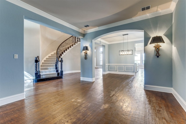 unfurnished living room with crown molding, an inviting chandelier, and dark hardwood / wood-style flooring