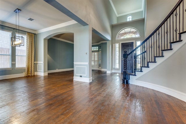 entrance foyer with a high ceiling, crown molding, dark wood-type flooring, and a wealth of natural light