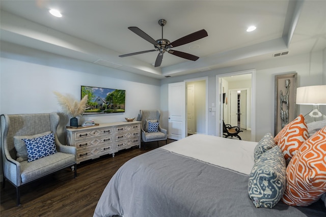 bedroom featuring dark hardwood / wood-style flooring, a tray ceiling, and ceiling fan