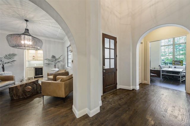 entryway featuring an inviting chandelier, ornamental molding, beverage cooler, and dark hardwood / wood-style floors