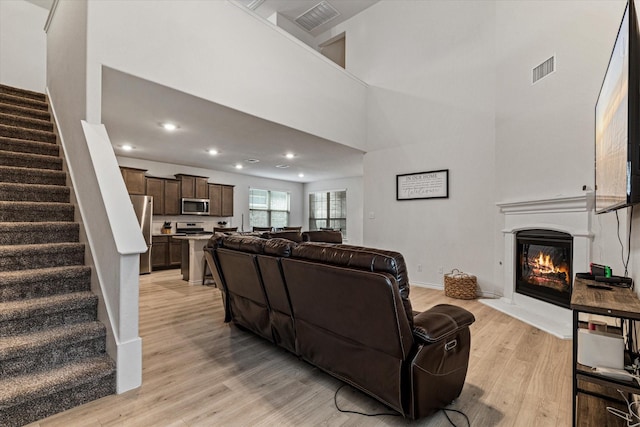 living room with a high ceiling and light wood-type flooring