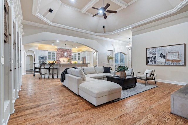 living room featuring a high ceiling, crown molding, ceiling fan, and light hardwood / wood-style flooring