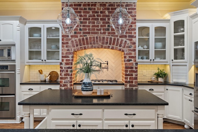 kitchen featuring stainless steel appliances, crown molding, backsplash, and decorative light fixtures