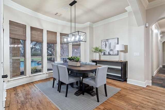 dining room featuring hardwood / wood-style flooring, ornamental molding, and a chandelier